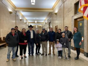 Group of folks connected to Justice for the People Legal Center stand in hallway of capitol building