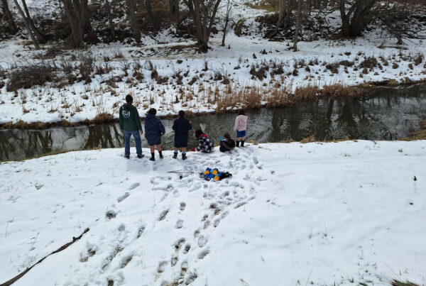 Five children play in the snow near the banks of a river