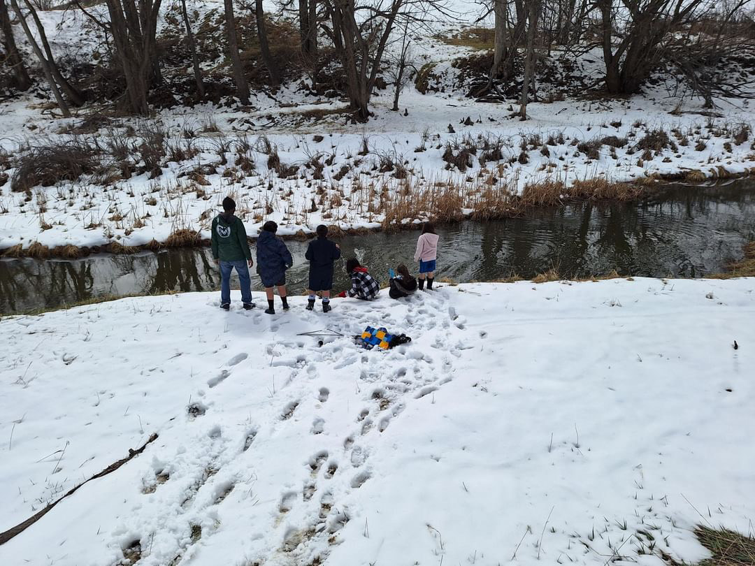 Five children play in the snow near the banks of a river