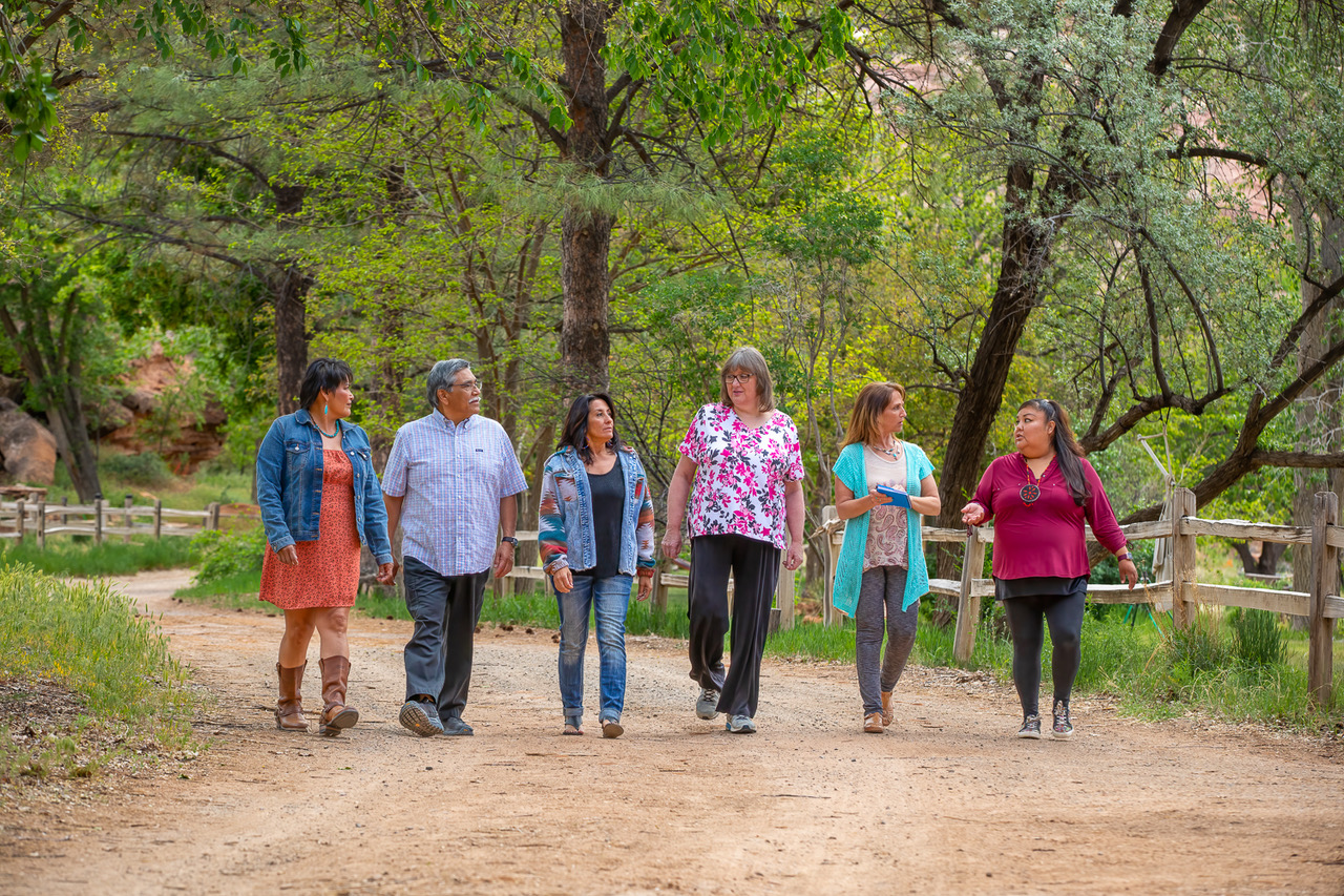 A group of Indigenous folks walk together outside on a path