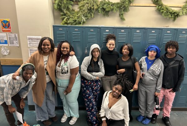 Group of Black youth smile at camera in school hallway