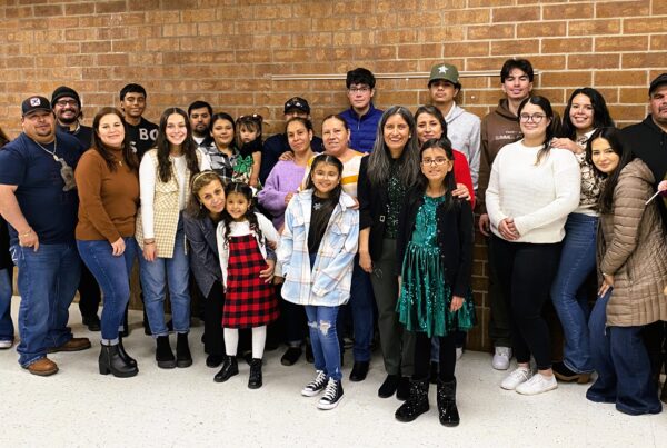 Large group photo of Latino parents and children smile at camera