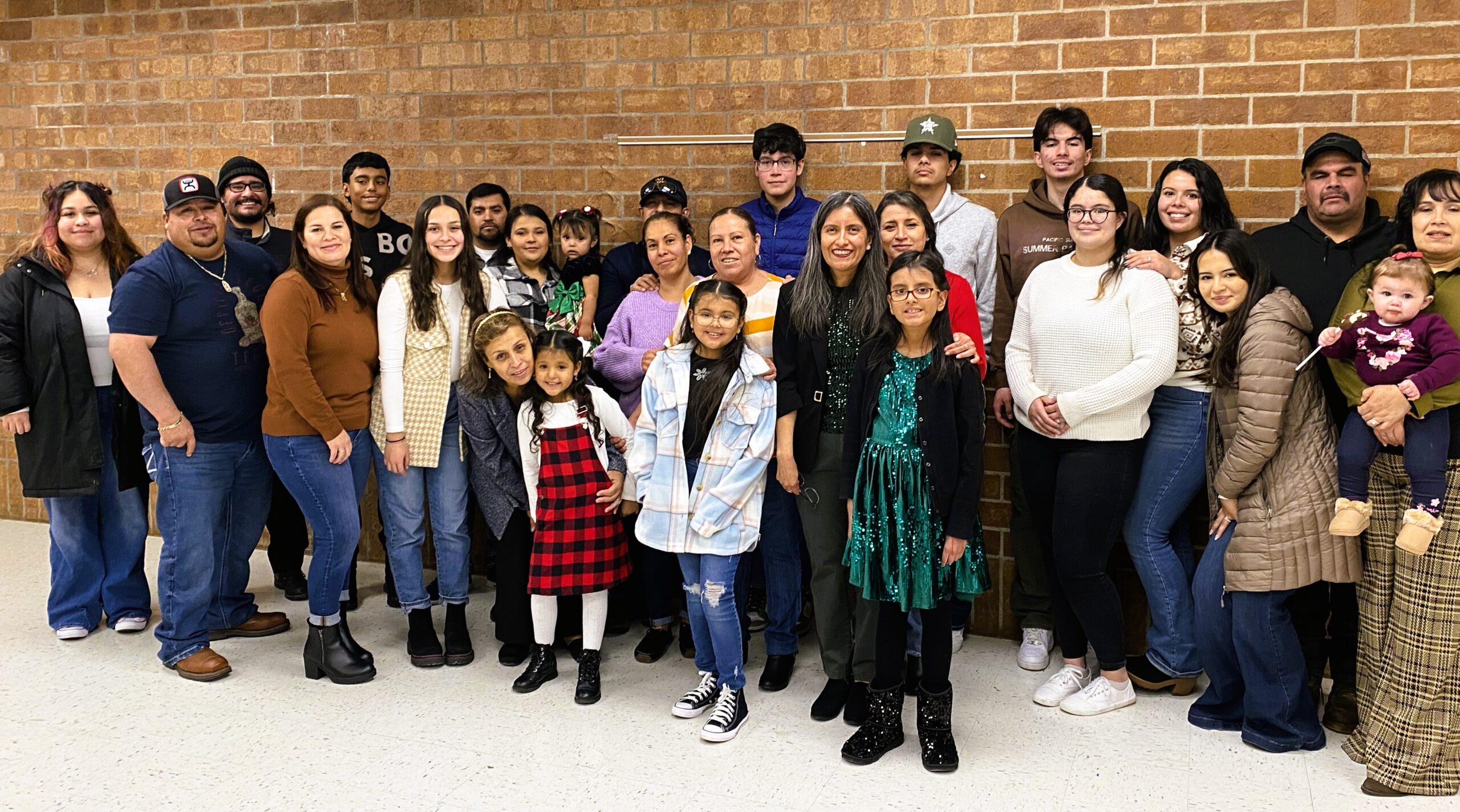 Large group photo of Latino parents and children smile at camera