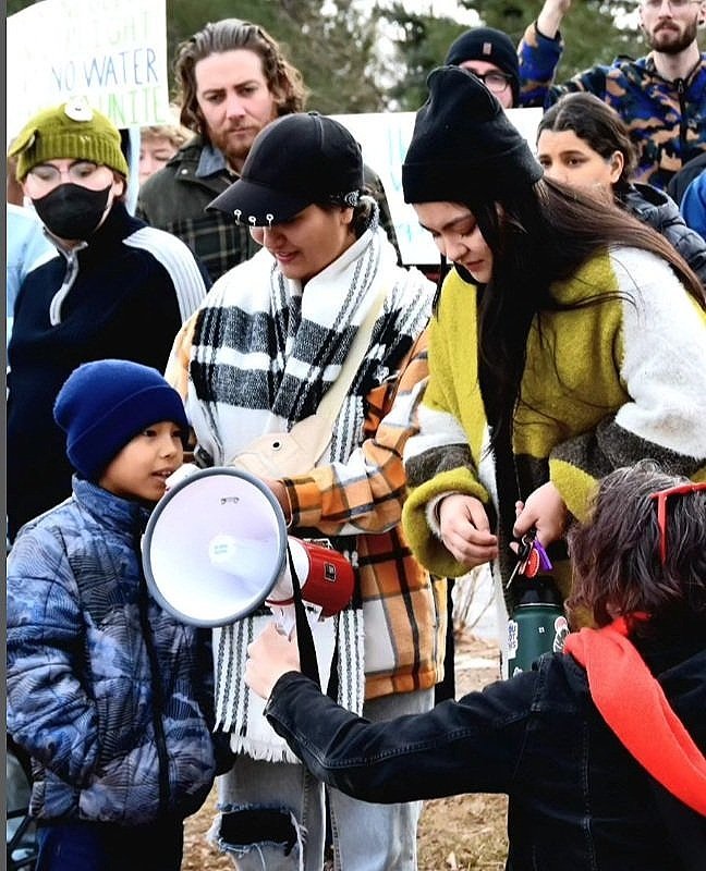Group of protestors gather around a megaphone