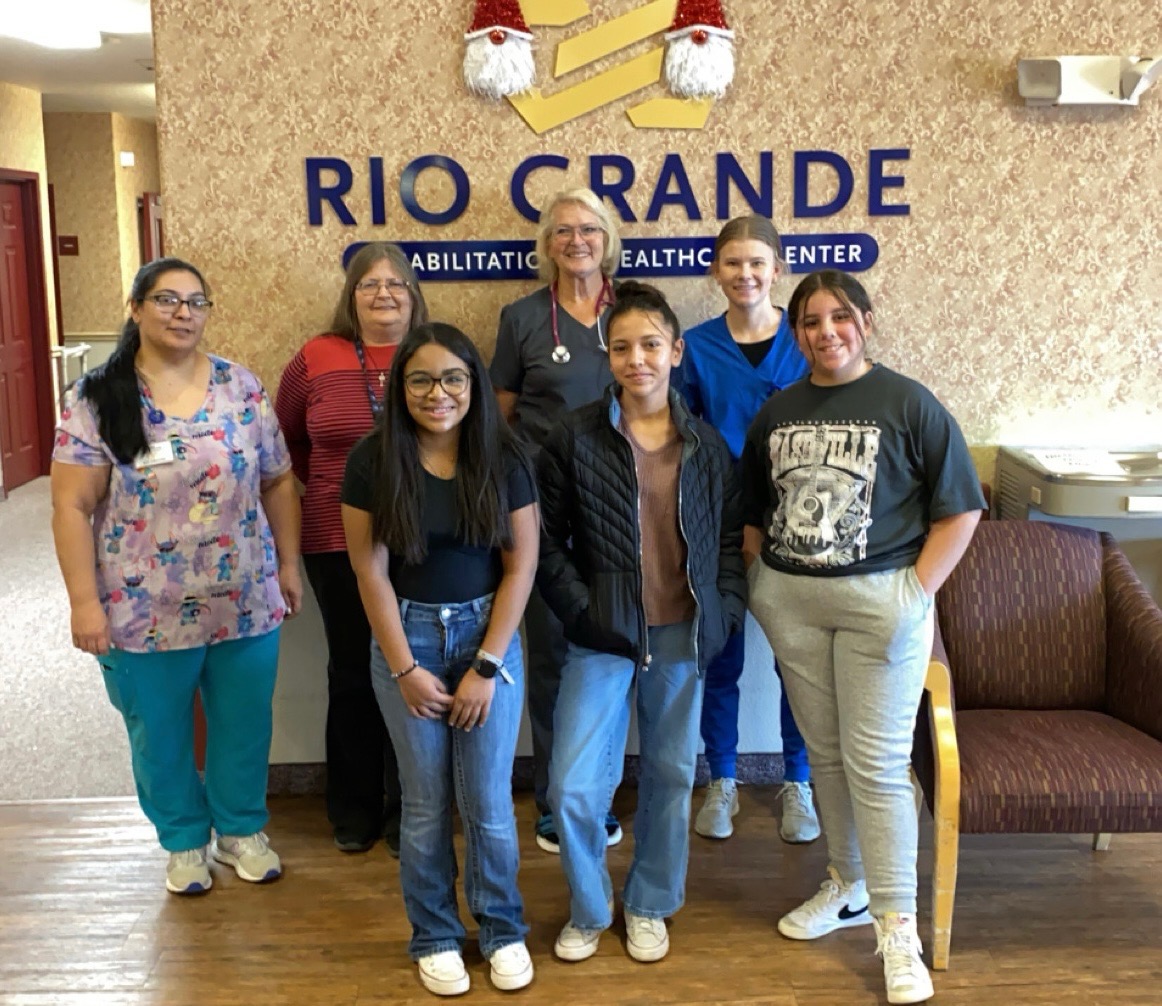 Three youth stand with four adults at a medical clinic