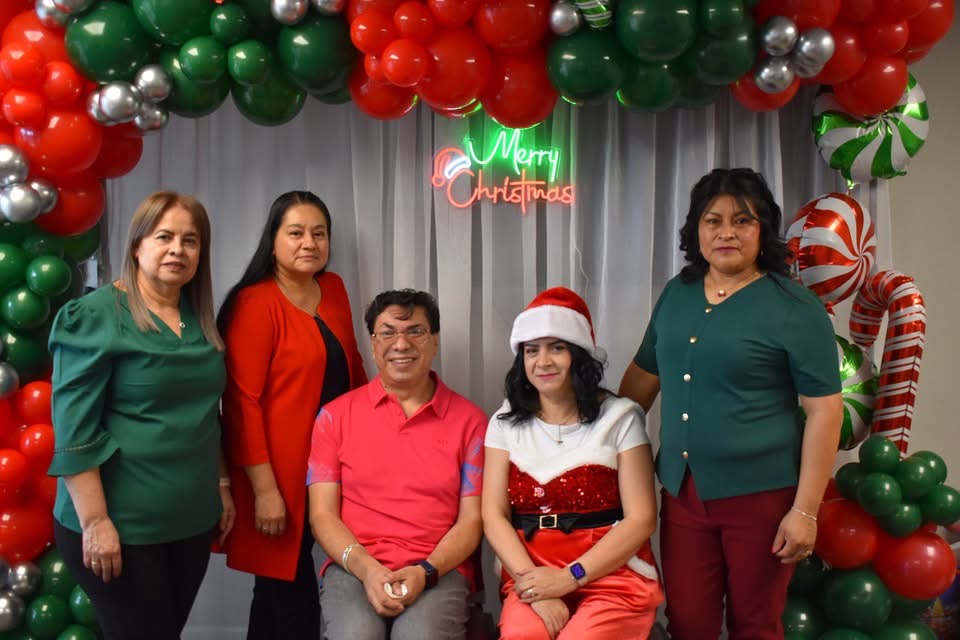 Five Latinx folks pose for a Christmas themed holiday photo